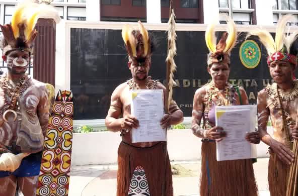 empat masyarakat adat Awyu dengan pakaian tradisional di depan gedung pengadilan