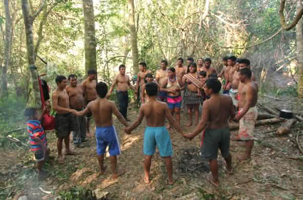 Masyarakat adat Ka'apor – anak-anak, perempuan dan laki-laki saling berpegangan tangan dan berdiri berlingkar di hutan hujan