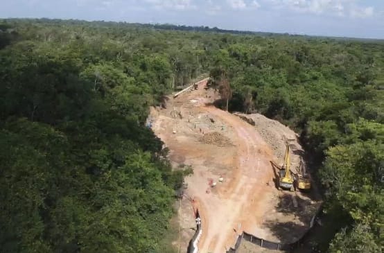 Foto pembangunan saluran pipa bauksit di hutan hujan dengan eskavator yang mengaduk-aduk tanah dan meletakkan pipa