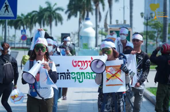 Sebuah kelompok mahasiswa berjalan dengan megafon dan spanduk melewati sebuah jalan