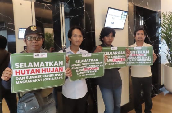 Empat warga dengan plakat bertuliskan “Selamatkan hutan hujan dan sumber kehidupan masyarakat Loeha Raya”