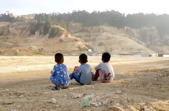 Tiga anak kecil memandang pertambangan pasir