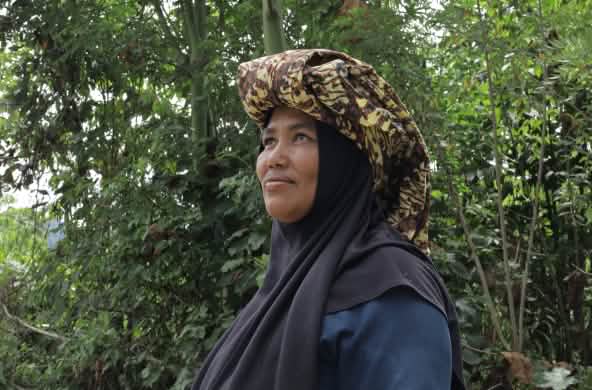 Perempuan dengan jilbab dan kain adat