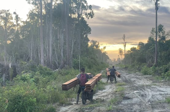 dua laki-laki membawa kayu dengan motor