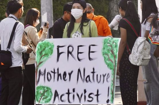 Mother Nature Activist! Seorang aktivis mengangkat plakat menghadap kamera dengan tulisan „Free Mother Nature Activist!