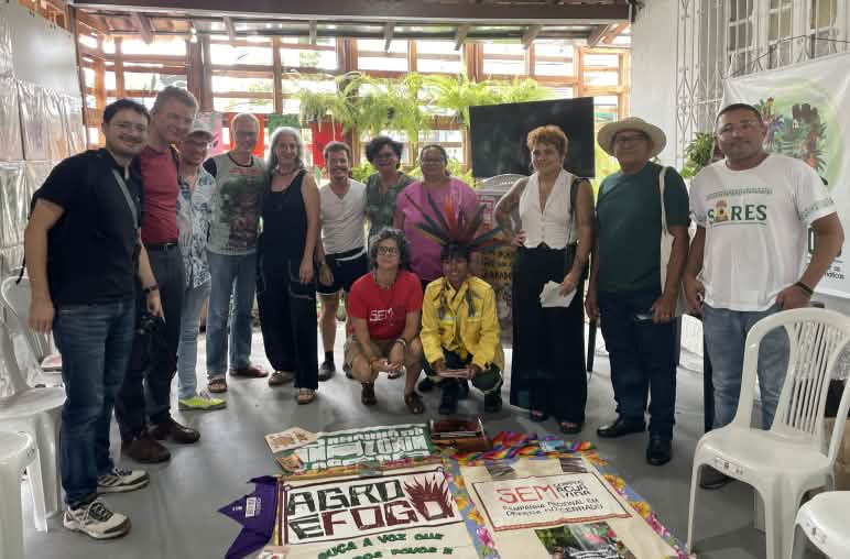 Sekelompok orang dengan latar depan perlengkapan materi proyek yang diletakkan di lantai di dalam ruang konferensi