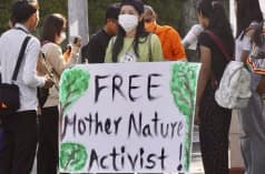 Mother Nature Activist! Seorang aktivis mengangkat plakat menghadap kamera dengan tulisan „Free Mother Nature Activist!
