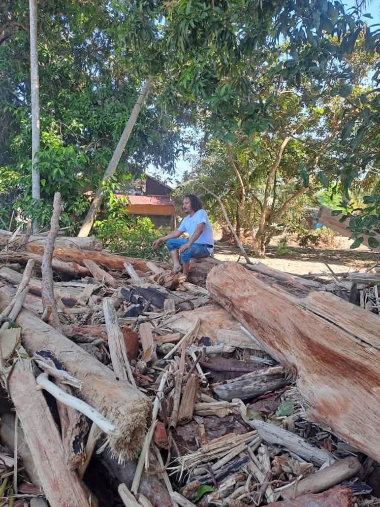Yusmadi duduk di atas puing-puing bangunan kantor AWF setelah badai siklon November 2025 lalu