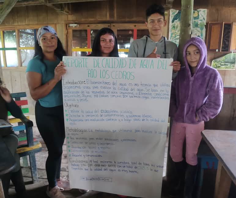 Empat remaja memegang kertas flipchart yang berisi rangkuman dari pendidikan tentang kualitas air yang telah mereka ikuti.