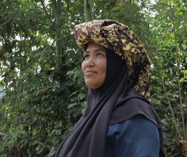 Perempuan dengan jilbab dan kain adat