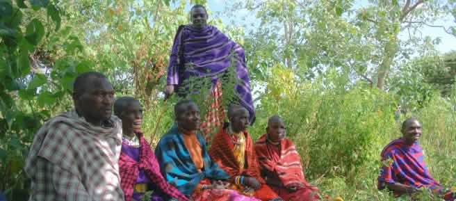 Sekelompok pria suku Maasai duduk di atas rumput dengan pakaian tradisional berwarna-warni