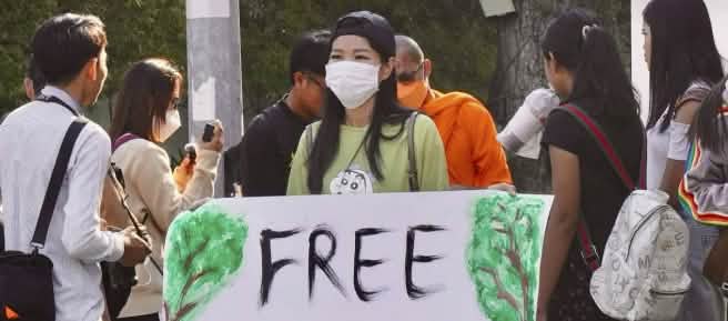 Mother Nature Activist! Seorang aktivis mengangkat plakat menghadap kamera dengan tulisan „Free Mother Nature Activist!