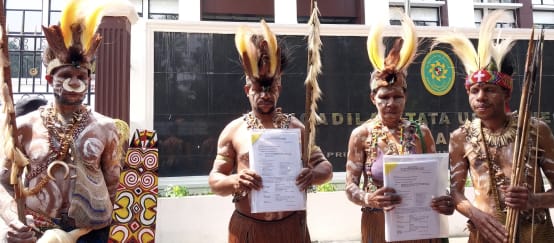 empat masyarakat adat Awyu dengan pakaian tradisional di depan gedung pengadilan