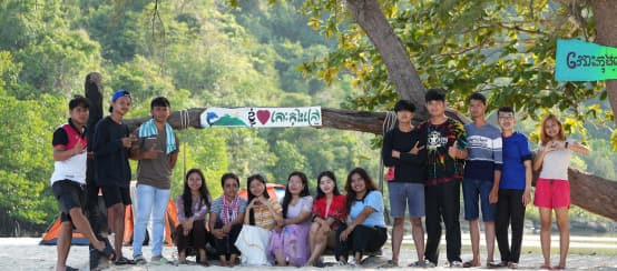 Kampanye bagi pulau Koh Kong: Tim anak muda dari Mother Nature Cambodia ingin menyelamatkan pulau tersebut dari eksploitasi liar (© Mother Nature Cambodia) Sebuah kelompok anak muda sedang duduk dan berdiri di depan pohon di pantai