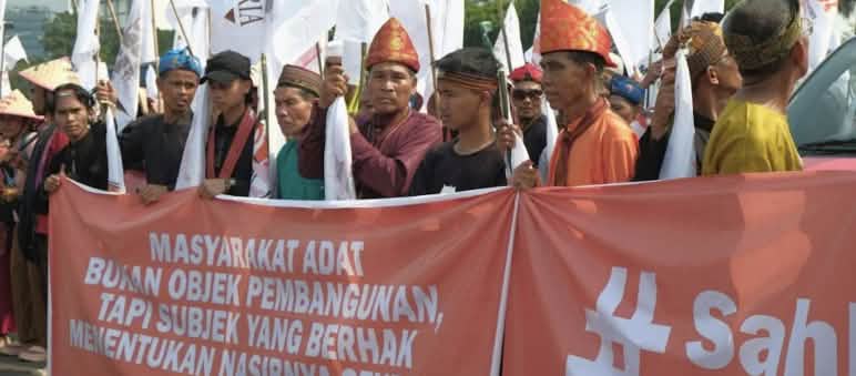 Masyarakat Adat bukan obyek pembangunan! Masyarakat Adat berhak menentukan nasibnya sendiri! Massa denga topi adat dan spanduk "Masyarakat adat bukan obyek pembangunan!"