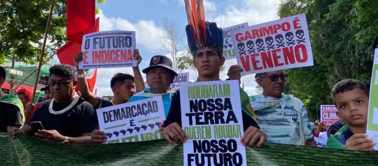 Protes selama KTT Amazonia, yang juga diadakan di Belém pada Agustus 2023. Masyarakat adat berbaris dan mengangkat poster dengan tulisan seperti: Tanah air kita adalah masa depan kita.