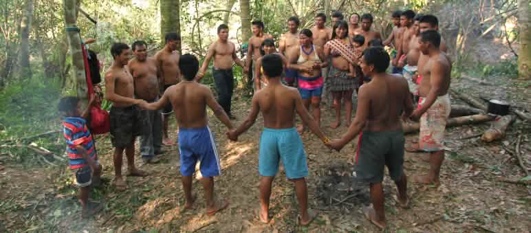 Masyarakat adat Ka'apor  – anak-anak, perempuan dan laki-laki saling berpegangan tangan dan berdiri berlingkar di hutan hujan