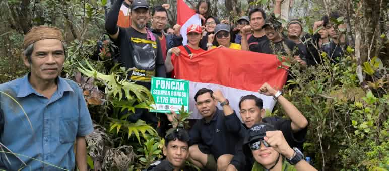 Tim pendaki yang ceria dengan bendera di dalam hutan