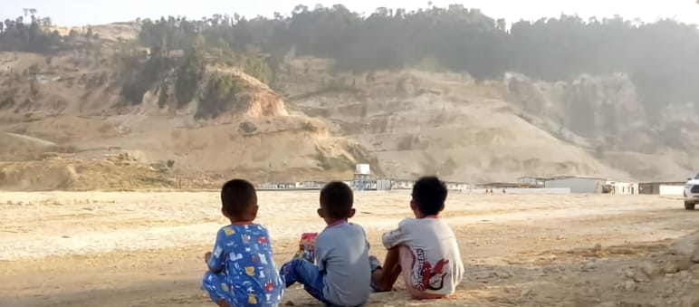 Tiga anak kecil memandang pertambangan pasir