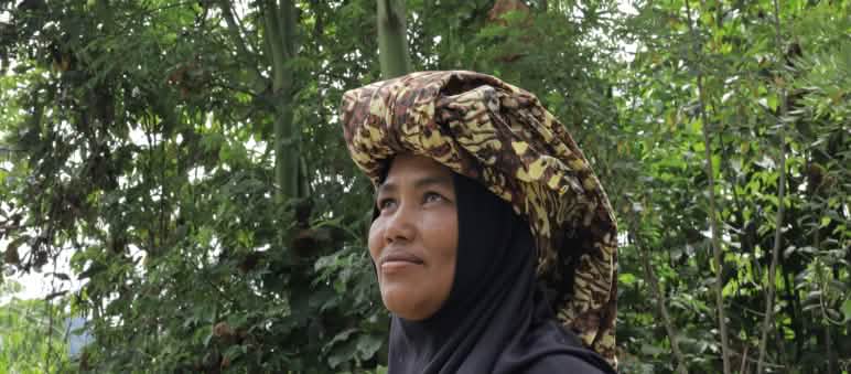 Perempuan dengan jilbab dan kain adat