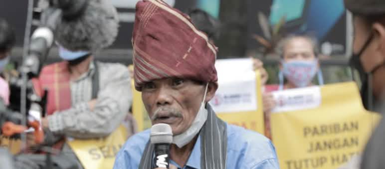 Seorang laki-laki Batak dengan tutup kepala khas dan mikrophone