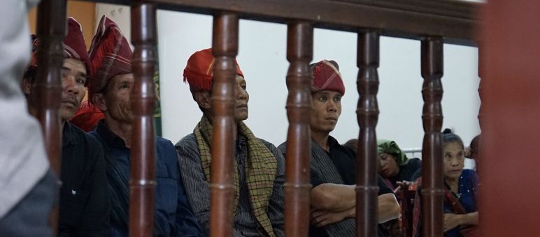 Laki-laki dengan topi Batak dibelakang pagar kayu