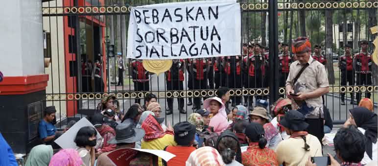 Demonstrasi di depan pagar tinggi dengan spanduk „Bebaskan Sorbatua Siallagan“