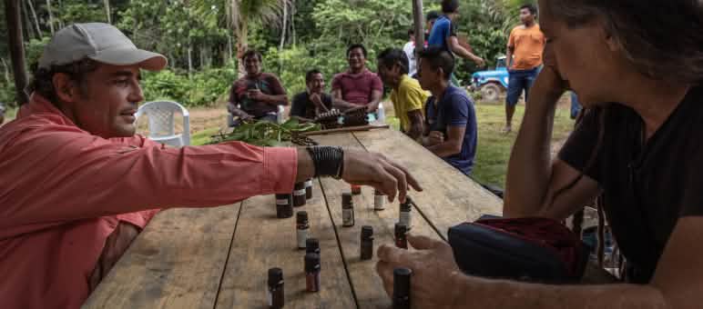 Dua pria berbicara tentang botol-botol kecil berisi minyak eteris yang berjejer di atas meja