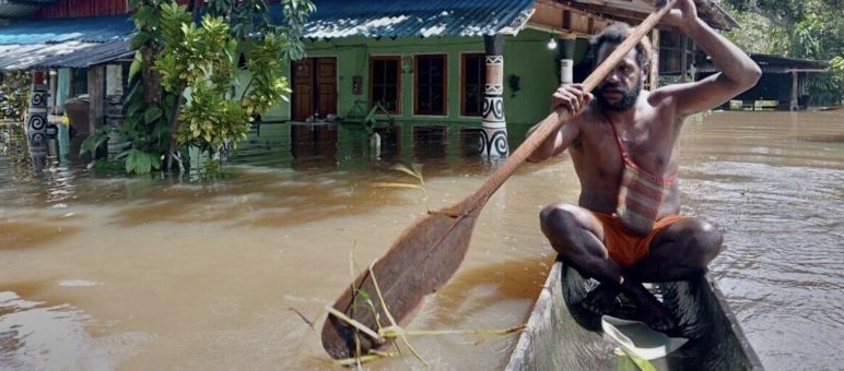 seorang laki-laki didalam perahu saat banjir di desa
