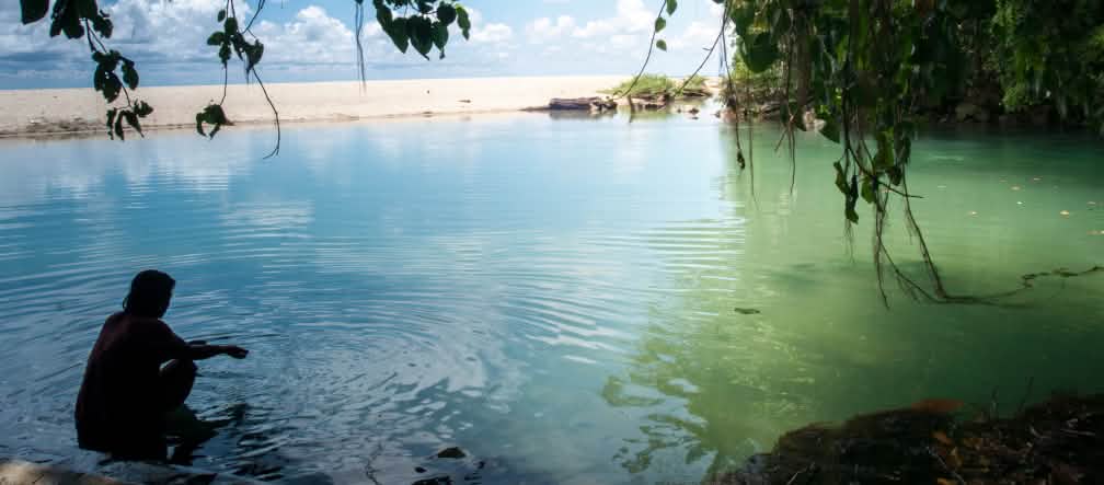 Sulawesi memiliki garis pantai sepanjang 6.000 kilometer dengan pantai berpasir, lereng terjal dan teluk yang tenang Seorang perempuan duduk di sebuah teluk yang berbatuan dan berpantai pasir.