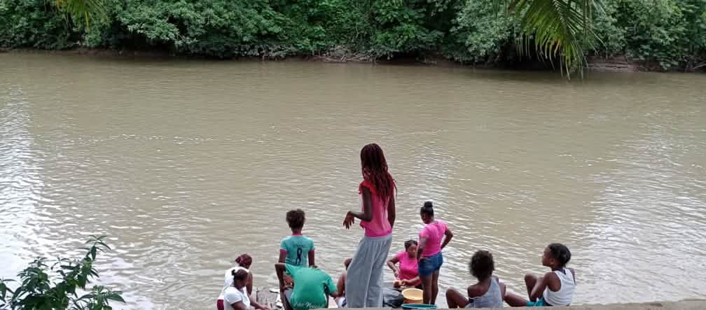 Sebuah kelompok perempuan di tepi sungai yang keruh di hutan hujan