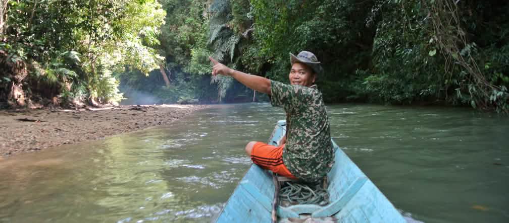 Masyarakat adat Iban merapatkan barisan menjaga hutan dan sungai mereka Seorang pria di tepi perahu kecil dengan antusiasnya menunjuk hutan hujan