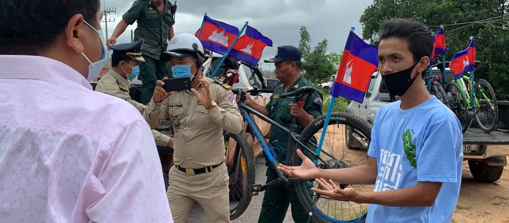 Para pencinta lingkungan berdiskusi dengan polisi yang memuat sepeda mereka ke dalam truk. Seorang petugas polisi memotret kejadian
