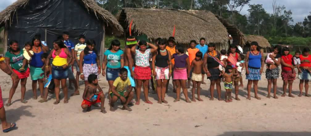 Masyarakat adat Kaapor berdiri membentuk dua barisan di depan gubuk di hutan hujan