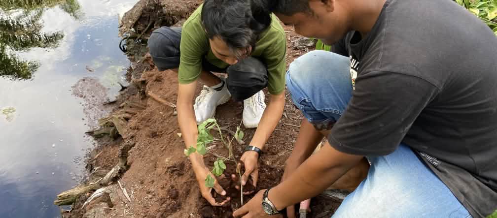 dua laki-laki menanam pohon disebelah kanal