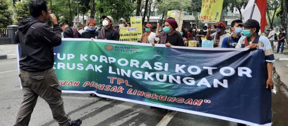 Fotograf dan para pendemo dengan spanduk hijau