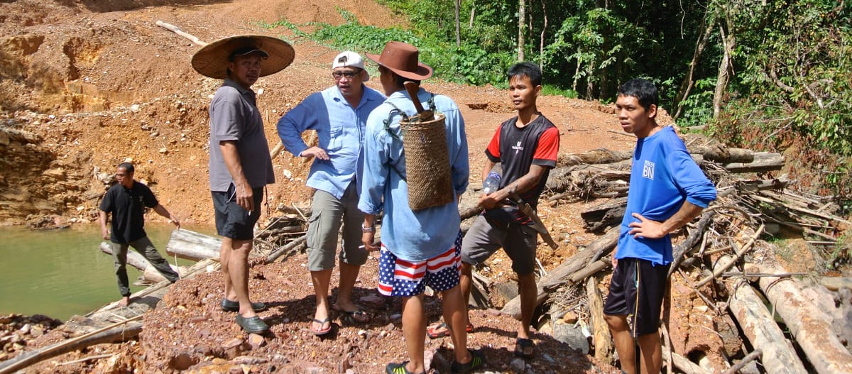 Masyarakat adat berdiri di jalan bertanah yang dibuat oleh penebang kayu secara ilegal di Sarawak