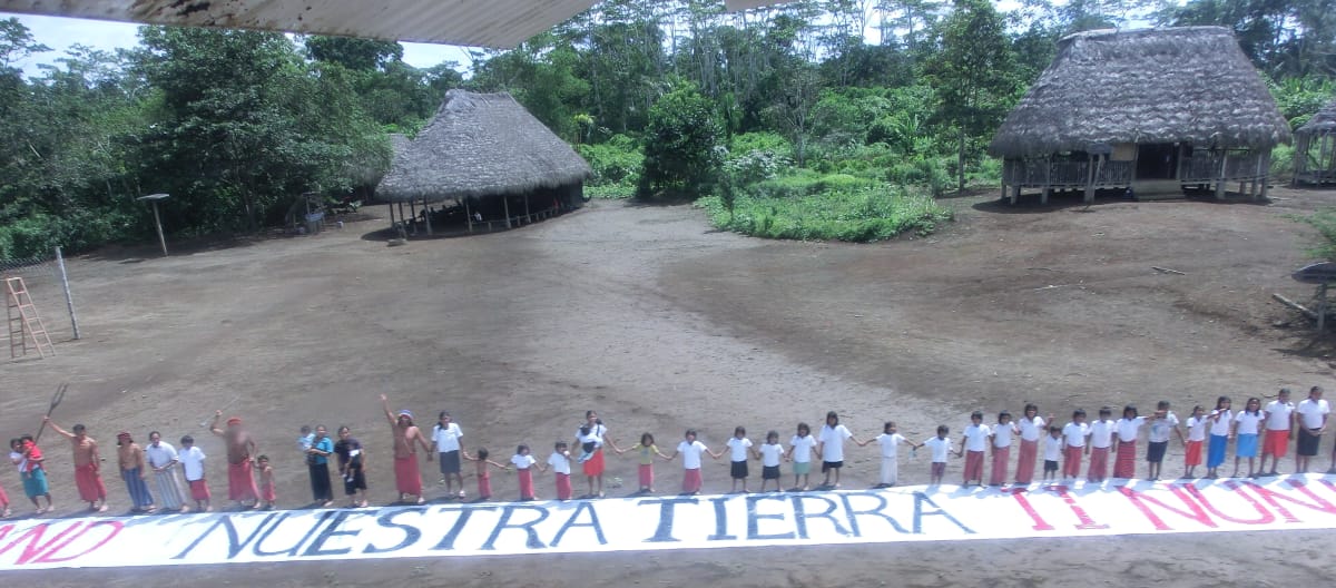 Tanah kita - nuestra tierra! Rantai manusia dengan spanduk menentang perampasan lahan di Ekuador