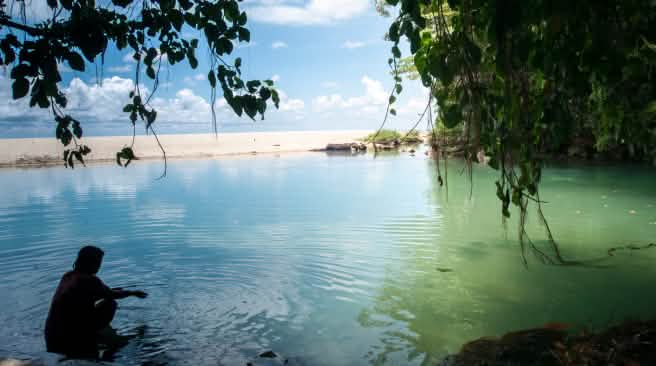 Sulawesi memiliki garis pantai sepanjang 6.000 kilometer dengan pantai berpasir, lereng terjal dan teluk yang tenang Seorang perempuan duduk di sebuah teluk yang berbatuan dan berpantai pasir.