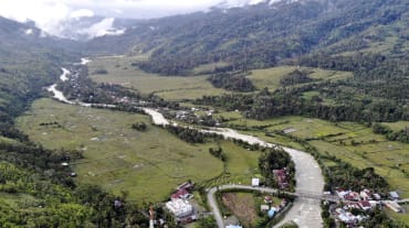 foto drone lembah dengan sungai dan kampung kecil