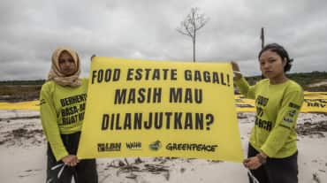 dua perempuan dengan spanduk "Food Estate gagal"