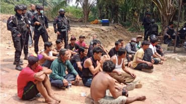 masyarakat adat tertangkap duduk didepan aparat polisi bersenjata