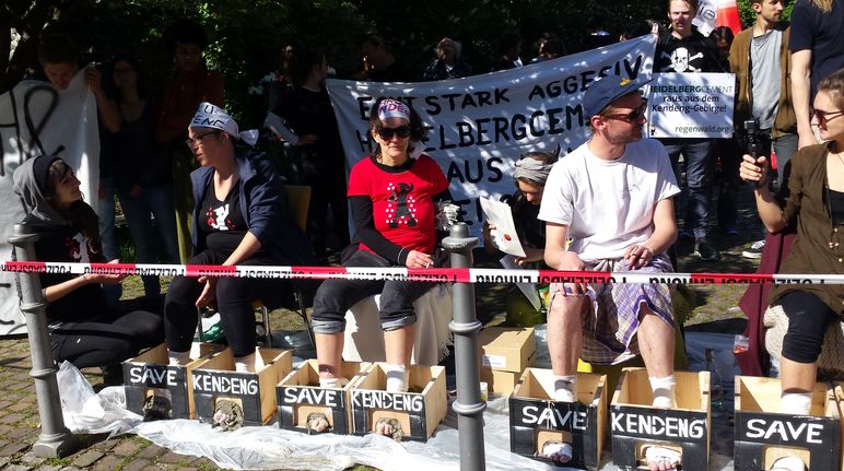 Protes di depan balai kongres Heidelberg: aktivis mencor kaki mereka dengan semen