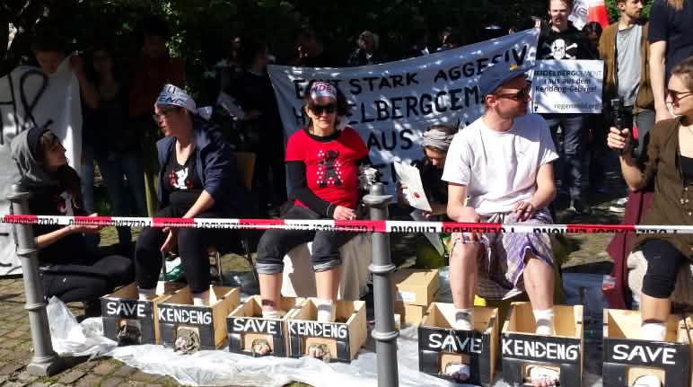 Protes di depan balai kongres Heidelberg: aktivis dengan kaki yang dicor semen Protes di depan balai kongres Heidelberg: aktivis mencor kaki mereka dengan semen