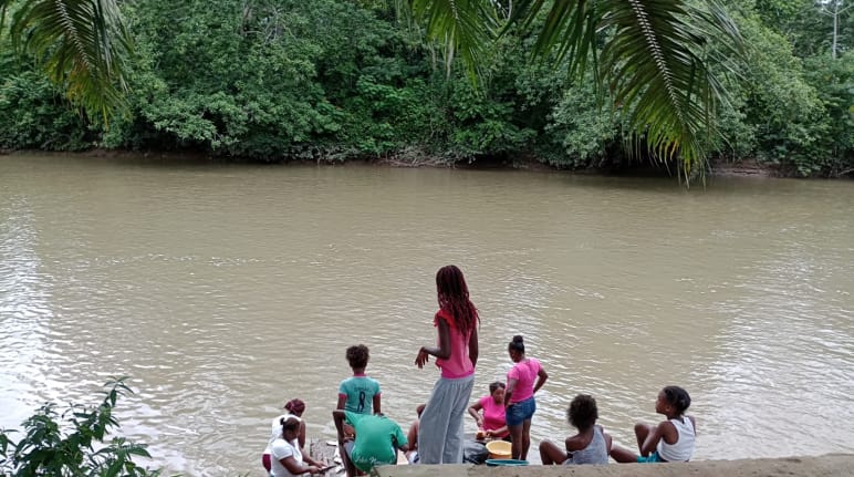 Sebuah kelompok perempuan di tepi sungai yang keruh di hutan hujan