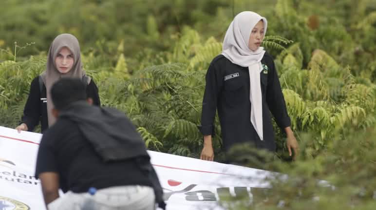 Koalisi Perempuan Jaga Lingkungan (KORJUANG) mengadakan aksi pembentangan spanduk di kawasan gambut Rawa Tripa dua perempuan dan spanduk