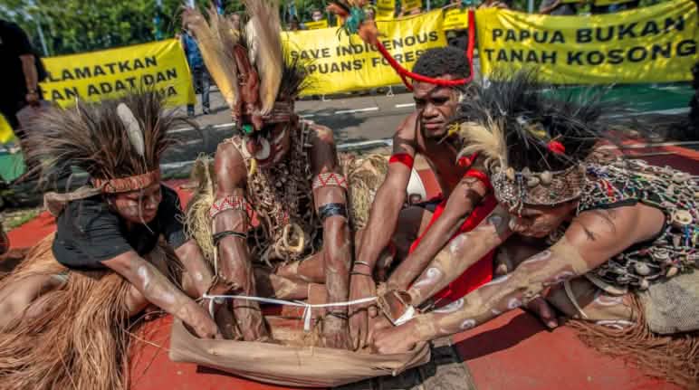 Ritual suku Awyu dengan tanah dari Boven Digoel-Papua di depan gedung Mahkamah Agung di Jakarta 27 Mei 2024 4 warga Papua dengan hiasan bulu burung di kepala sedang melakukan ritual. „Papua bukanlah tanah kosong“