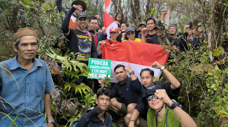 Setibanya di puncak, kami menggelar ritual dengan penuh khidmat dan memohon izin kepada roh leluhur agar mau mengabulkan hajat pendaki, terutama masyarakat adat Dayak Tomun. Tim pendaki yang ceria dengan bendera di dalam hutan