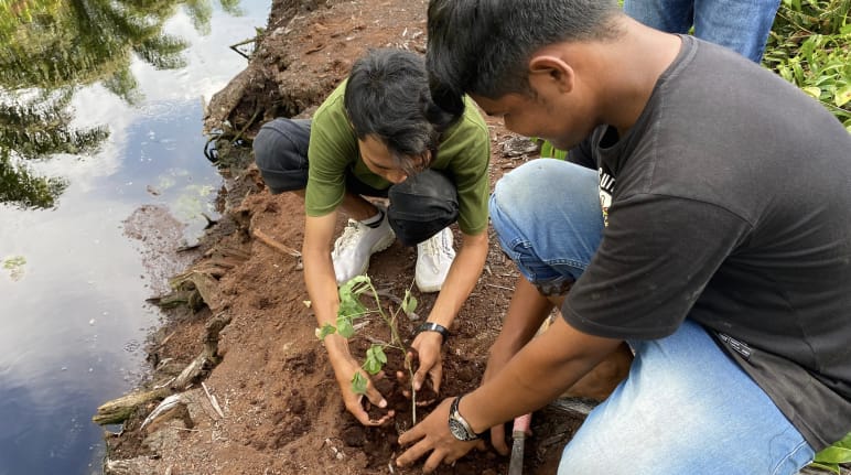 dua laki-laki menanam pohon disebelah kanal