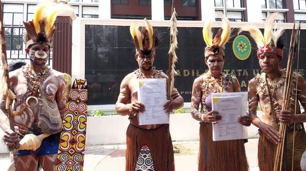 empat masyarakat adat Awyu dengan pakaian tradisional di depan gedung pengadilan